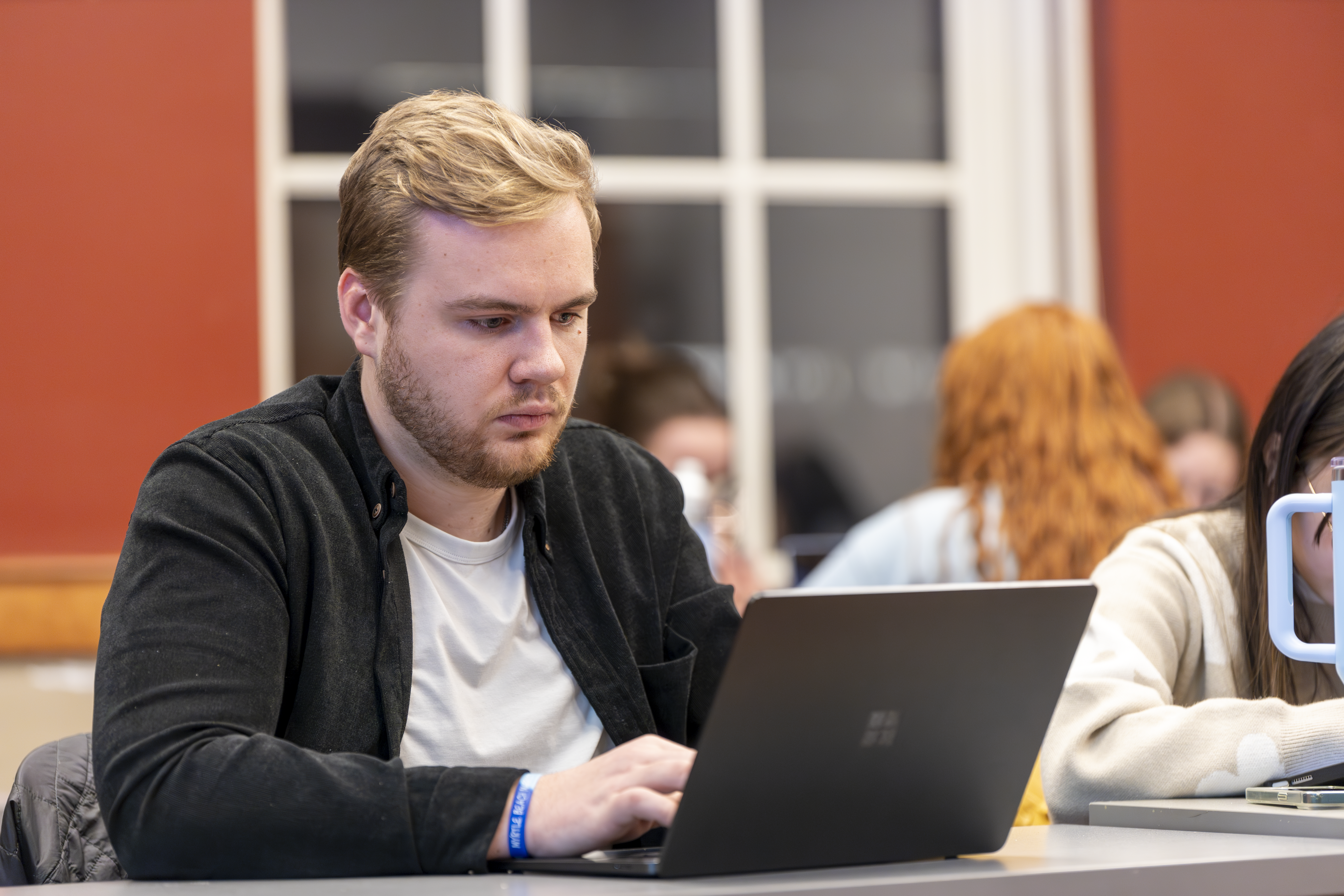 White male on laptop in classroom
